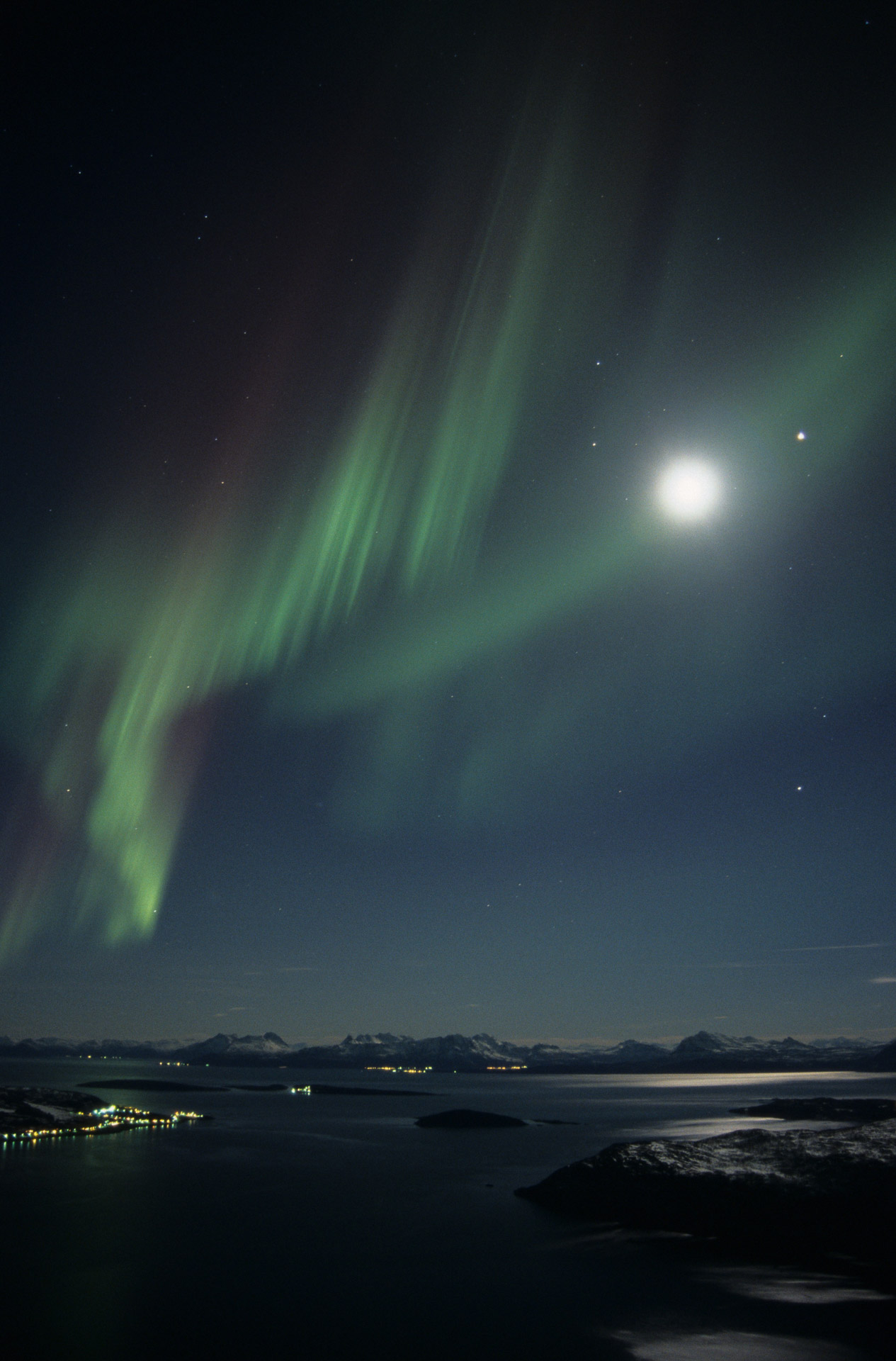 Northern lights with Harstad illuminated by moonlight © Frank Andreassen