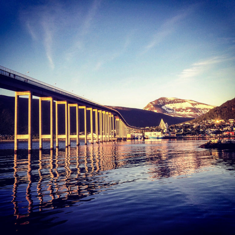 Midnight Sun shining on the Tromsø Bridge, the Arctic Cathedral and afar Mount Tromsdalstind © Knut Hansvold