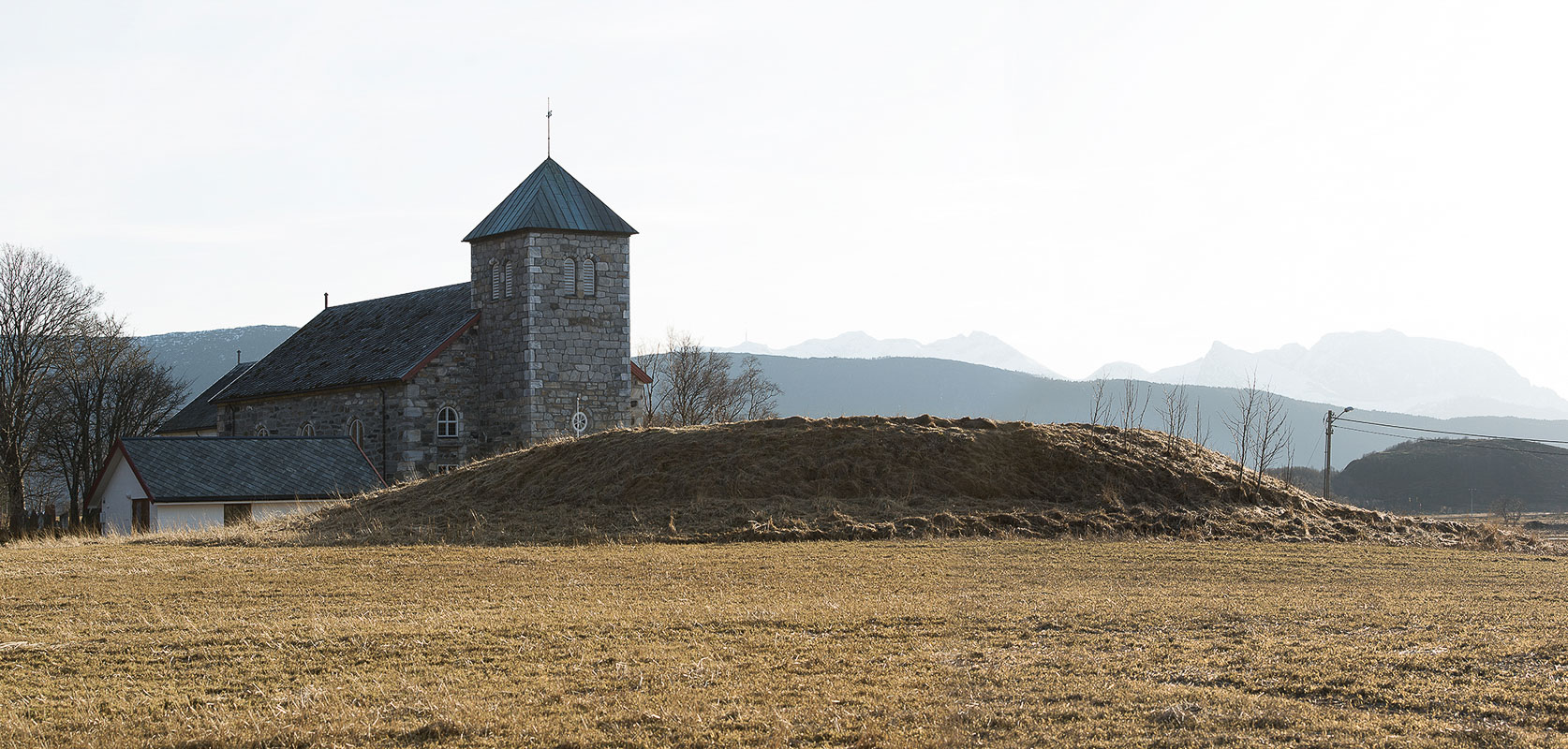 Sigarshaugen is the mound in the front, and the Steigen church is in the back © Ernst Furuhatt
