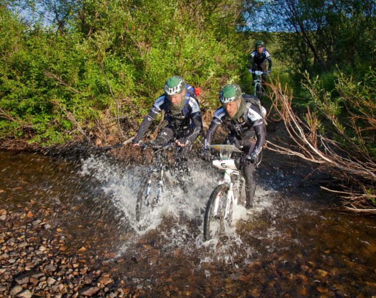 Crossing a creek with helmet nets for protection against the billions of mosquitos and midges that make the streams and lakes home during summertime © Offroadfinnmark Losvar