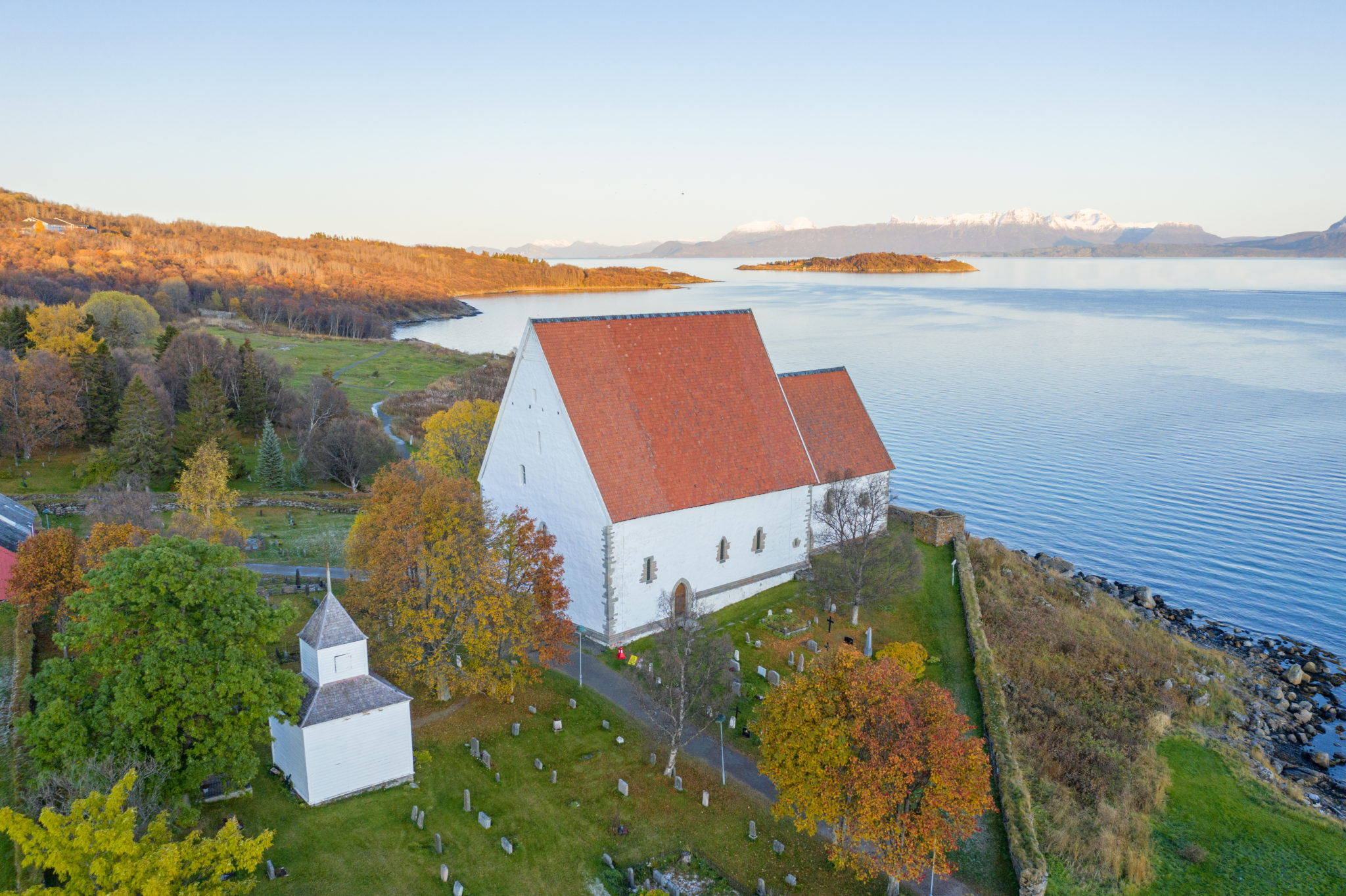 Trondenes kirke i høstskrud. Legg merke til restene av et tårn til høyre for koret i kirken © Jan Schmitt/ Visit Harstad