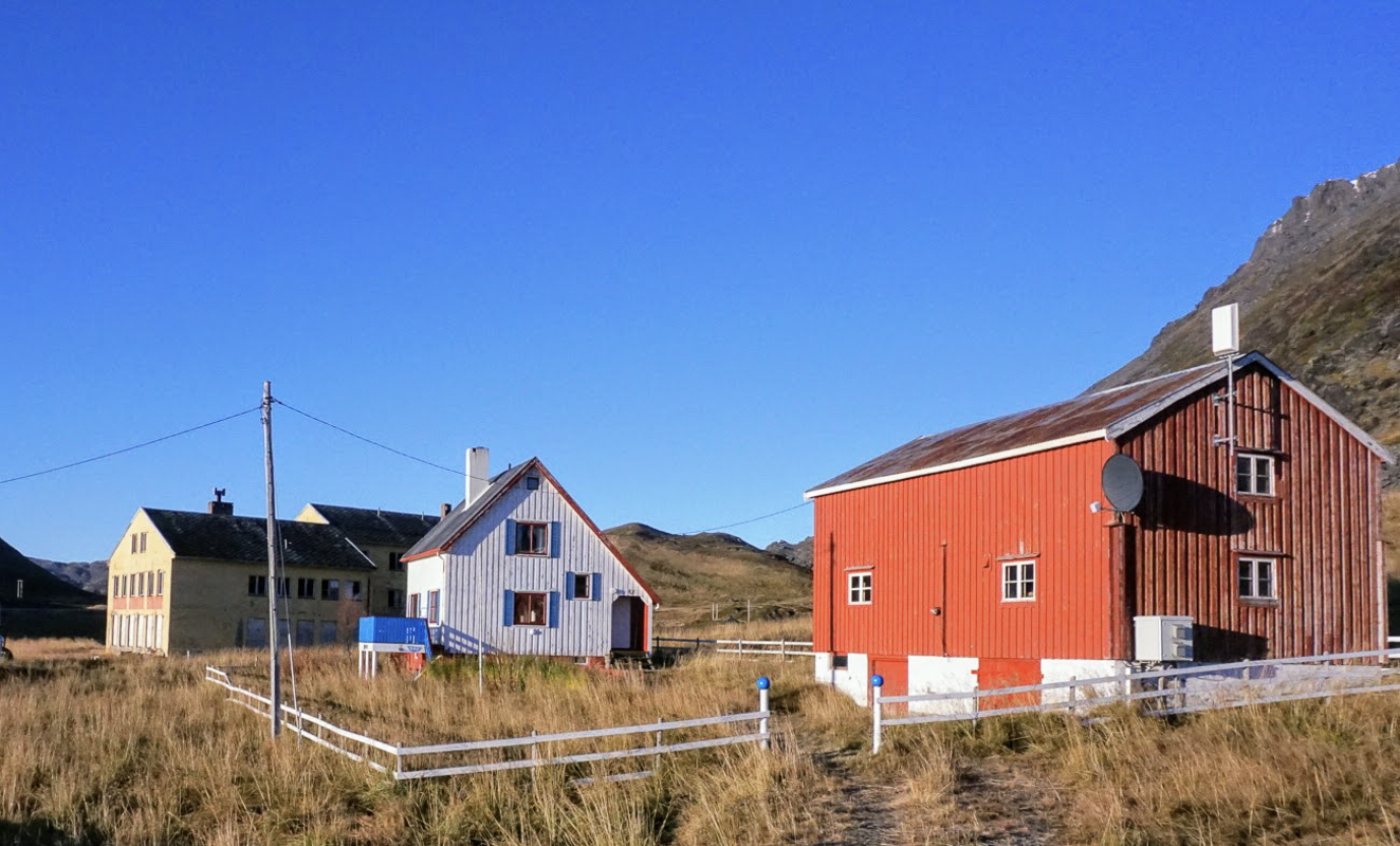 Gjenreisningsgård på Sarnes ved Honningsvåg, med et gjenreisningshus og en rødmalt låve. Like bortenfor ligger det gamle internatet fra 1958 © Knut Hansvold
