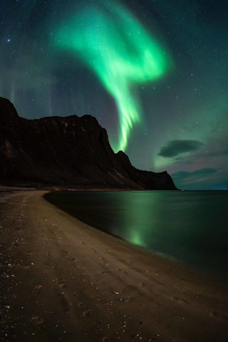 Aurora emerging over Senja's cliffs © Kristoffer Vangen