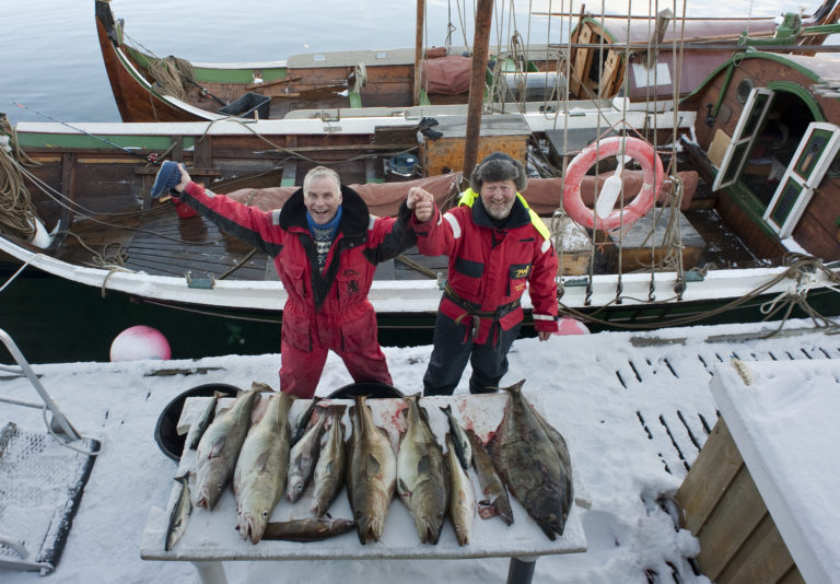 Happy fishermen at the Lofoten fishery with their traditional Nordlandsbåt. Foto: Ernst Furuhatt / nordnorge.com