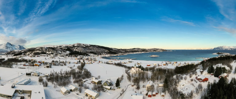 Vinterlig utsikt over Bjarkøy. Kirken ligger til høyre, og havna midt i bildet © Øivind Arvola /  Harstad kommune