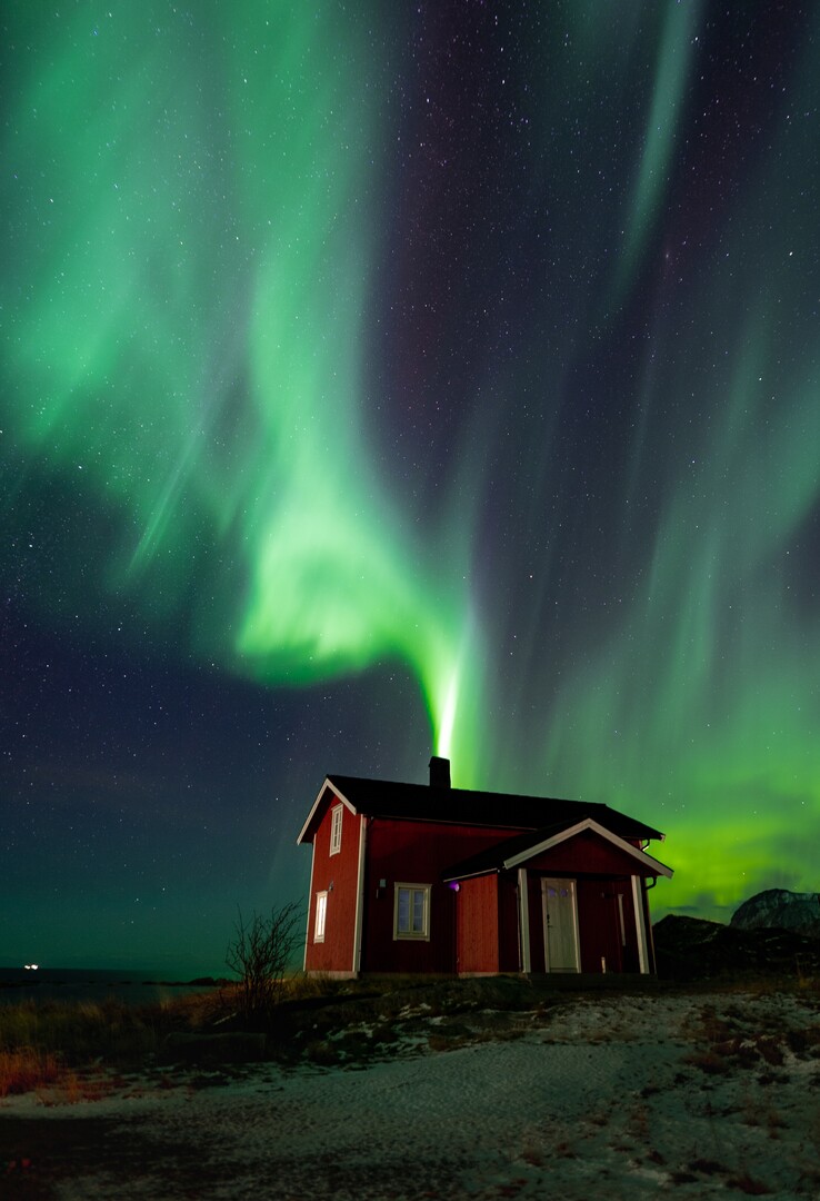 The Northern Lights seemingly come out of the chimney © Petr Pavlíček/Visit Lyngenfjord