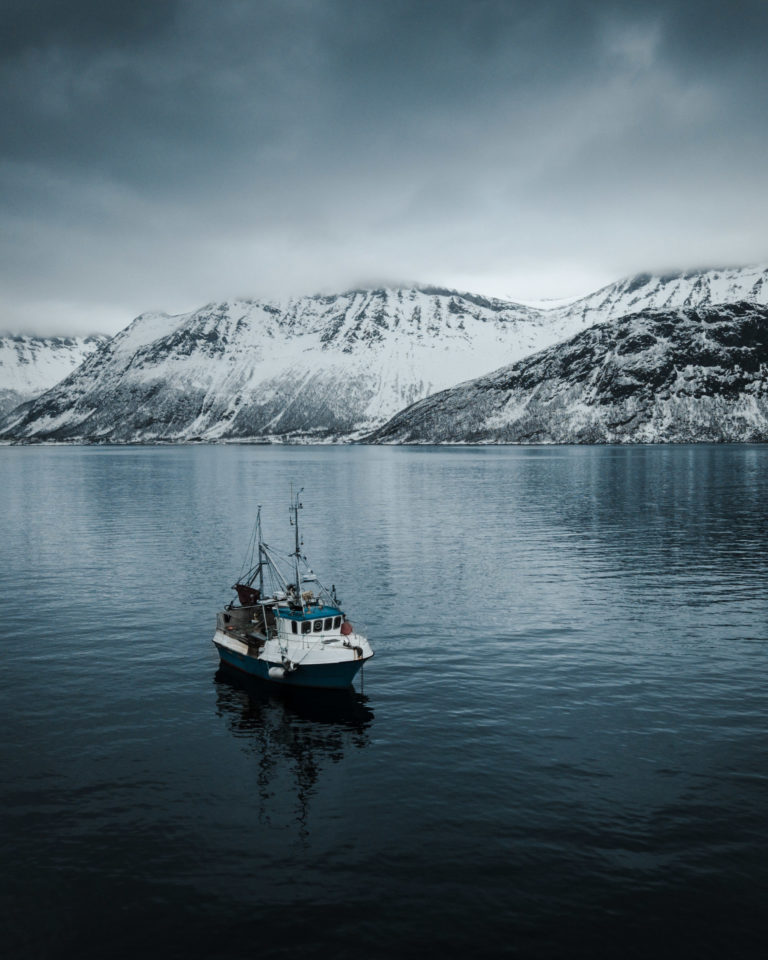 A fishing boat amid the snow clouds on Senja Island's ocean side © Kristoffer Vangen
