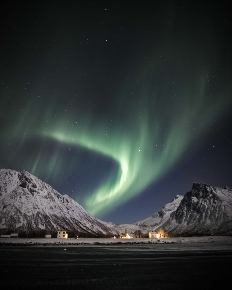 The Northern Lights forming an arch over the mountains on Senja Island © Kristoffer Vangen