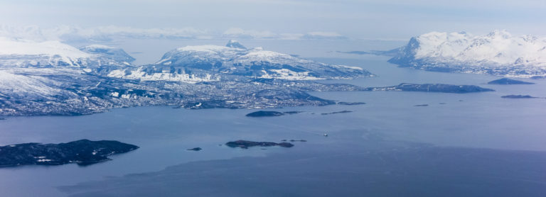 Winter image in grey and blue from Harstad. The city is in the centre, and the Trondenes peninsula juts out to the right. Behind it, you see the waterway of Toppsundet, and a at the far right the peaks of Grytøya island © Øivind Arvola / Harstad kommune