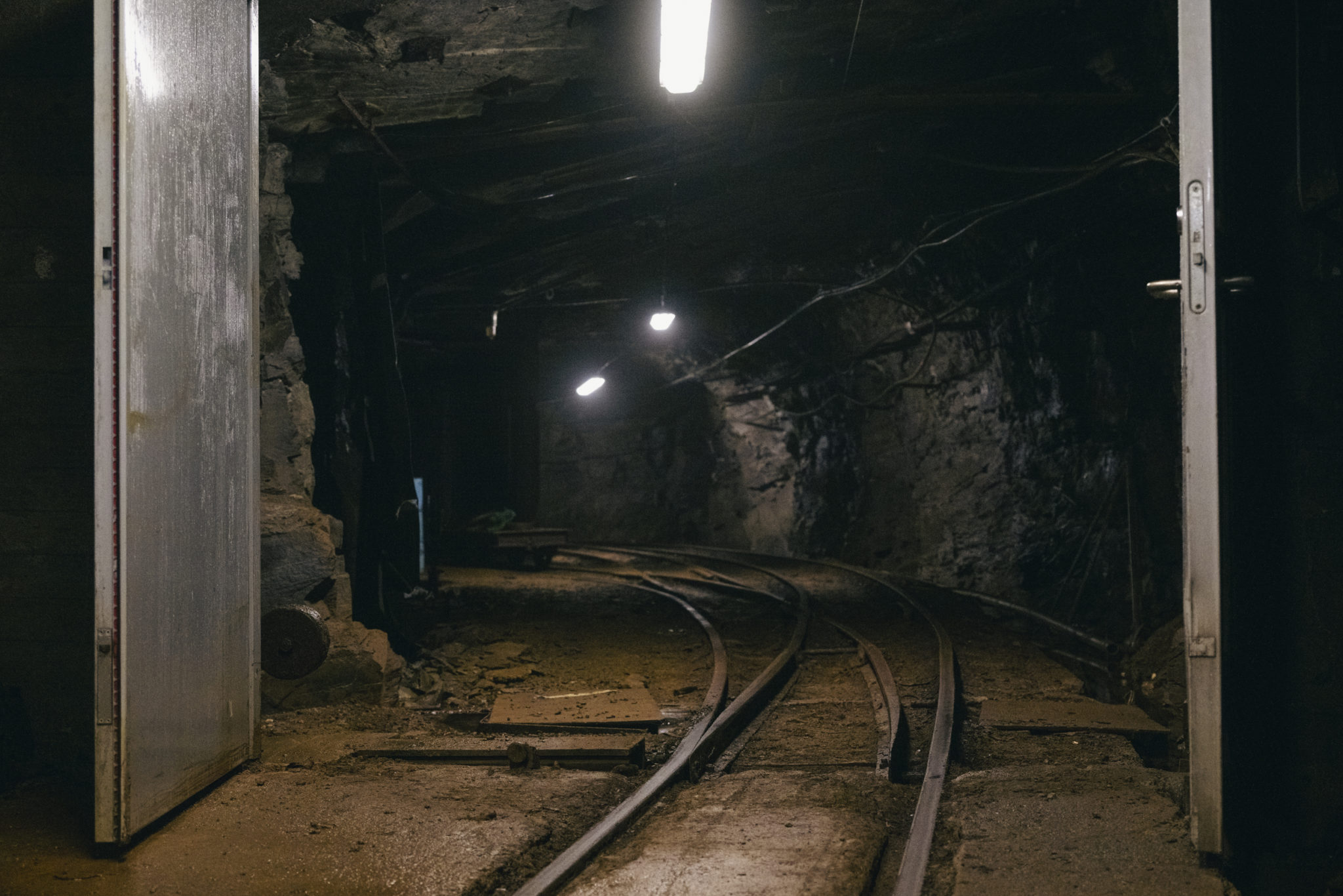 Inngang til besøksgruven i Sulitjelma gruver, med togskinner som går inn i det mørke fjellet. © Marie Nystad Helgesen 