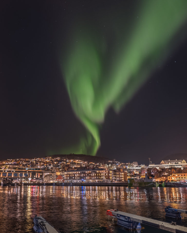 The Northern Lights swirl from the Folkeparken hills over the centre of Harstad © Arne Widding