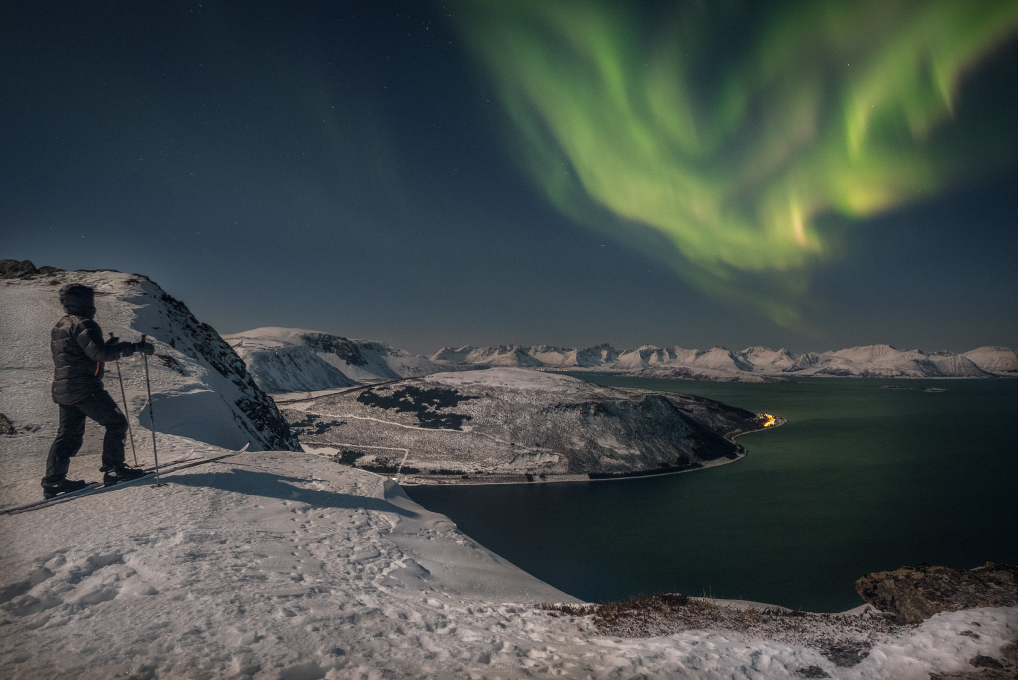 View from the mountain north of Harstad towards the northern lights dancing over the peaks of Grytøya © Arne Widding