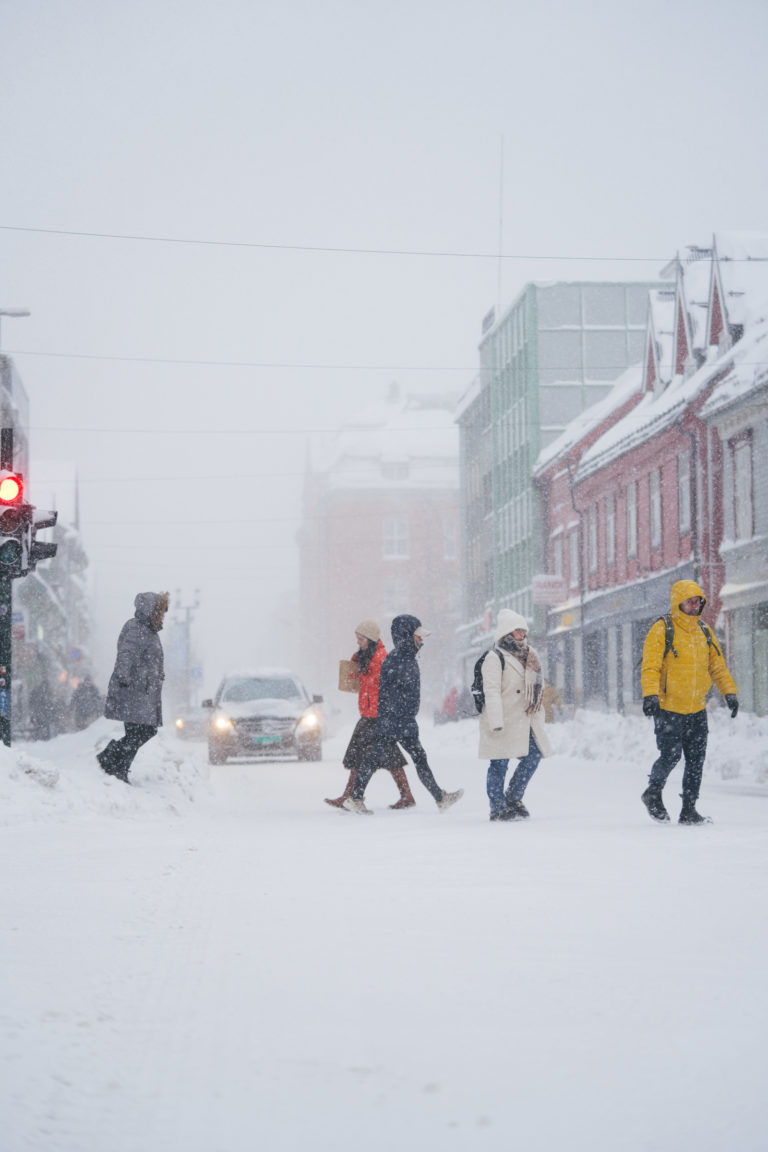Heavy snow showers in Storgata, Tromsø, as people climb over snowbanks to cross the street © David Jensen / @jensenmedia